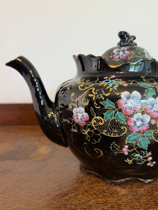 c.1920s–1930s vintage black ceramic teapot with hand-painted floral decoration, gold detailing, scalloped rim and matching lid.