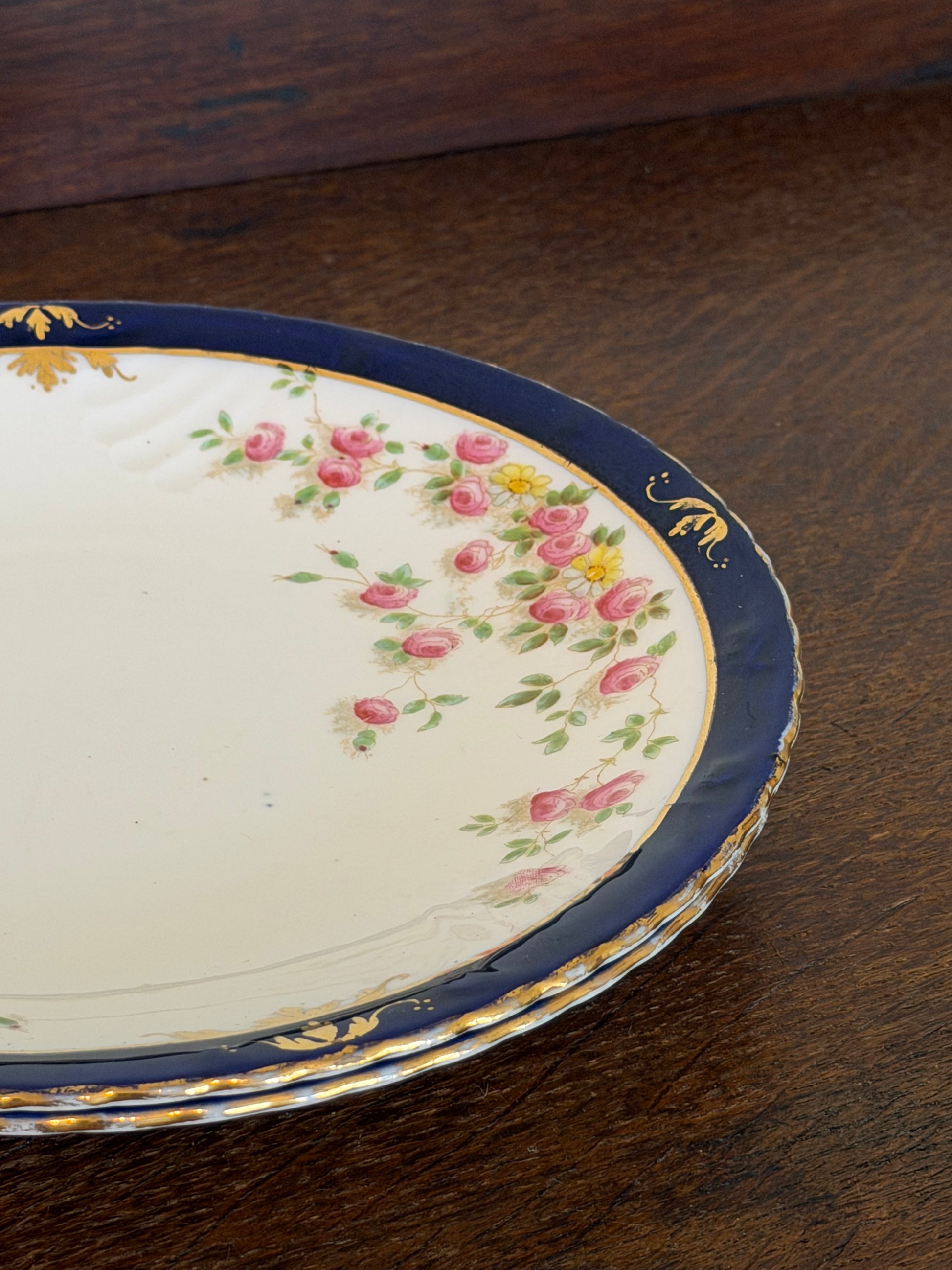 Pair of antique Royal Crown Derby porcelain plates with cobalt blue borders, pink rose garland decoration and hand-gilded detailing.