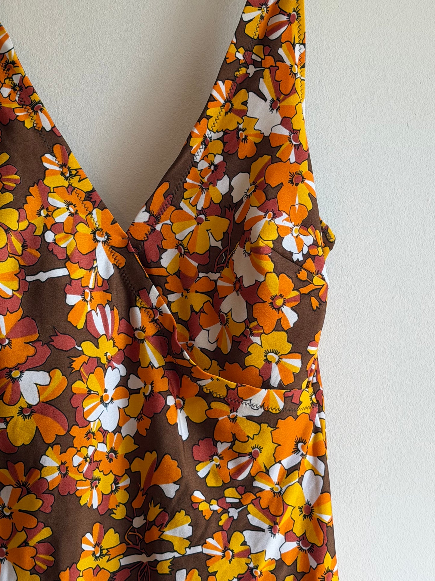 Vintage 1970s brown floral swimdress with wrap neckline and attached briefs in orange, mustard and white floral print.
