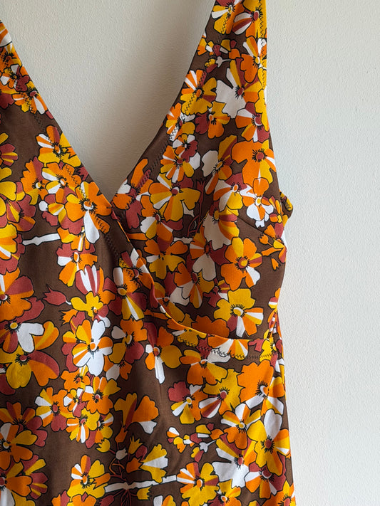 Vintage 1970s brown floral swimdress with wrap neckline and attached briefs in orange, mustard and white floral print.