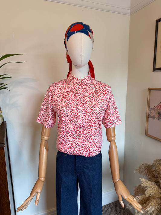 Vintage red and white geometric print blouse with pointed collar, short sleeves and front button fastening, styled with dark blue jeans.