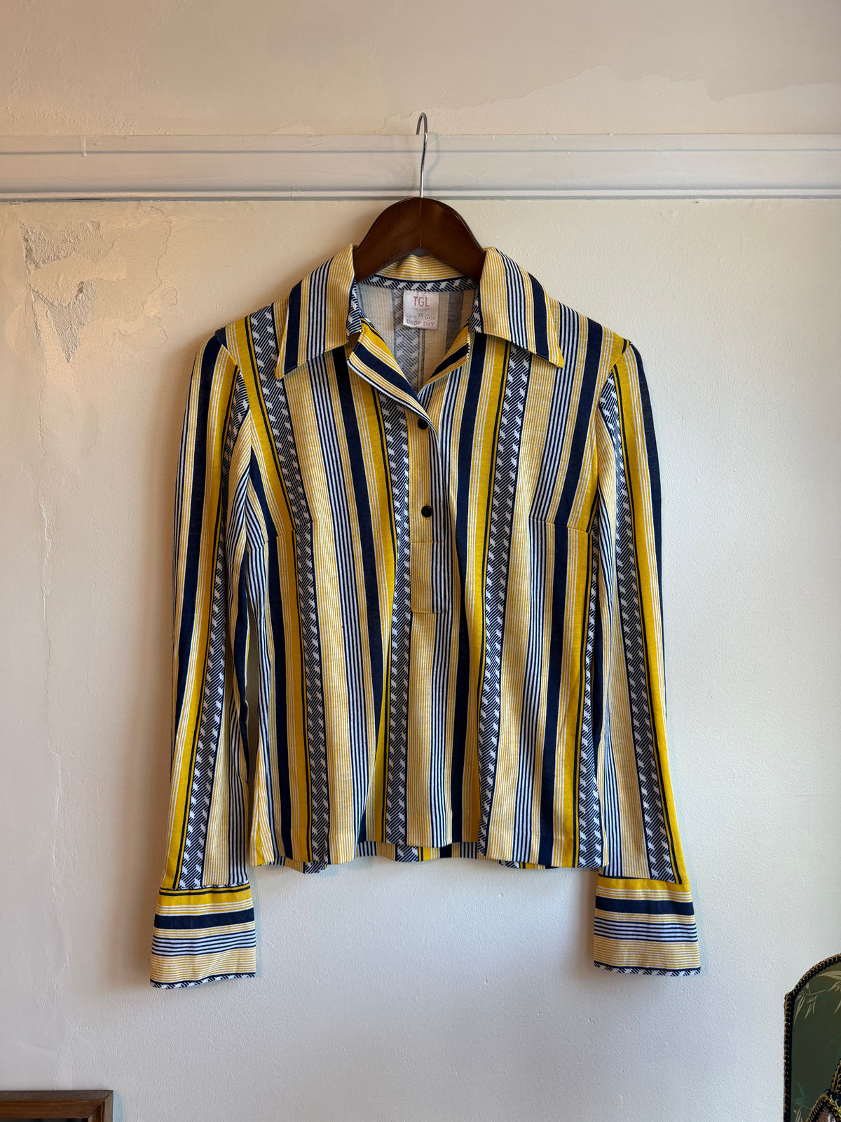 Vintage 1970s TGL Stockholm long-sleeved shirt with mustard yellow, navy blue, white and grey vertical stripes, geometric pattern panels, pointed collar and wide flared cuffs.