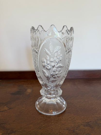 Vintage Zaječar 24% lead crystal vase with a pedestal foot and scalloped rim. The clear crystal features frosted oval floral panels with raised berry and leaf motifs surrounded by cut detailing. Photographed against a neutral background on a dark wooden surface.