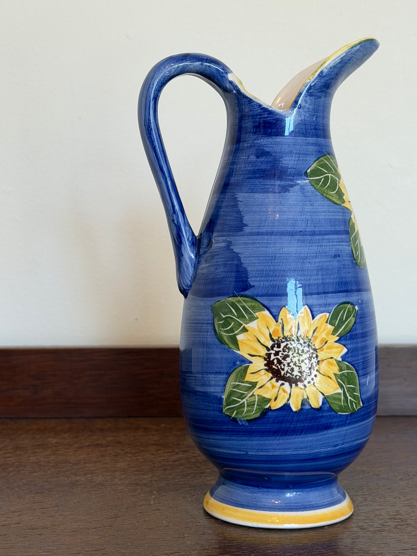 Hand-painted vintage cobalt blue ceramic jug featuring yellow sunflower decoration with a curved handle and pouring spout.
