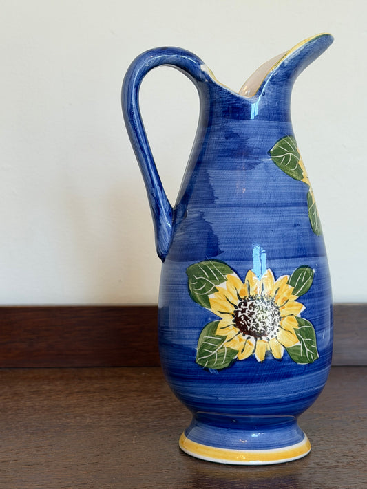 Hand-painted vintage cobalt blue ceramic jug featuring yellow sunflower decoration with a curved handle and pouring spout.
