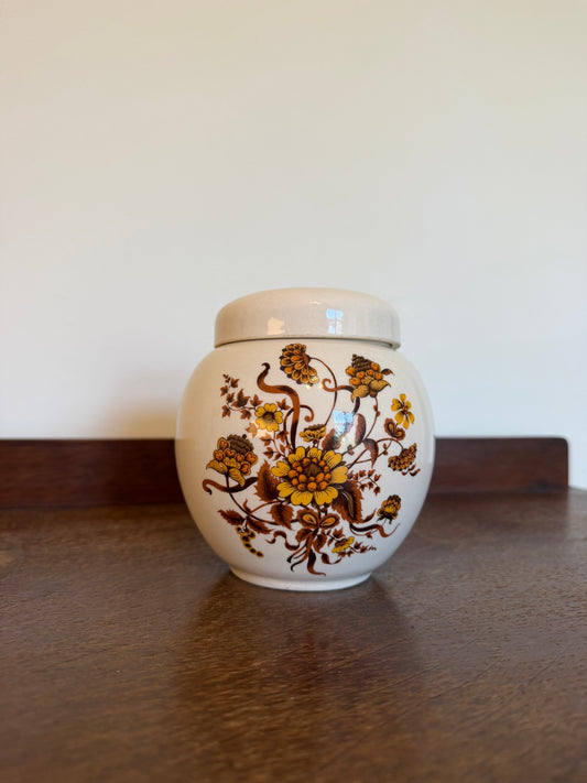 Vintage late 1960s-1970s Sadler England ceramic ginger jar with matching lid, featuring a cream glaze and mustard yellow, ochre and brown floral botanical transfer pattern. Rounded shape with fitted lid, photographed against a neutral background.
